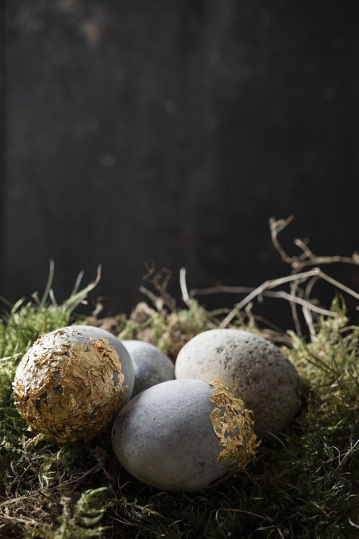 Easter eggs painted with stone effects and gold leaf on moss