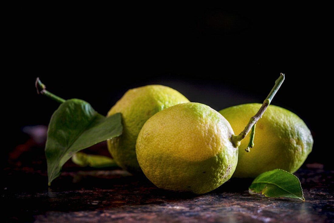 Drei Zitronen mit Stiel und Blättern