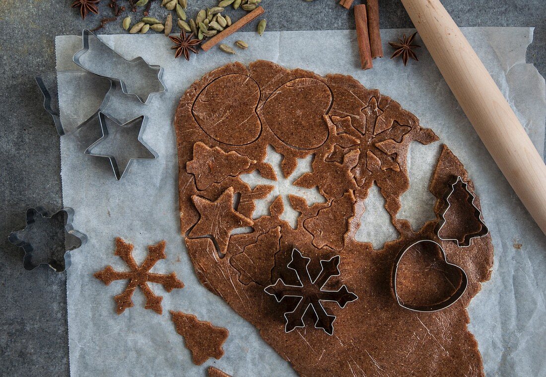 Vegan gingerbread biscuits being cut out of a rolled-out sheet of pastry (seen from above)