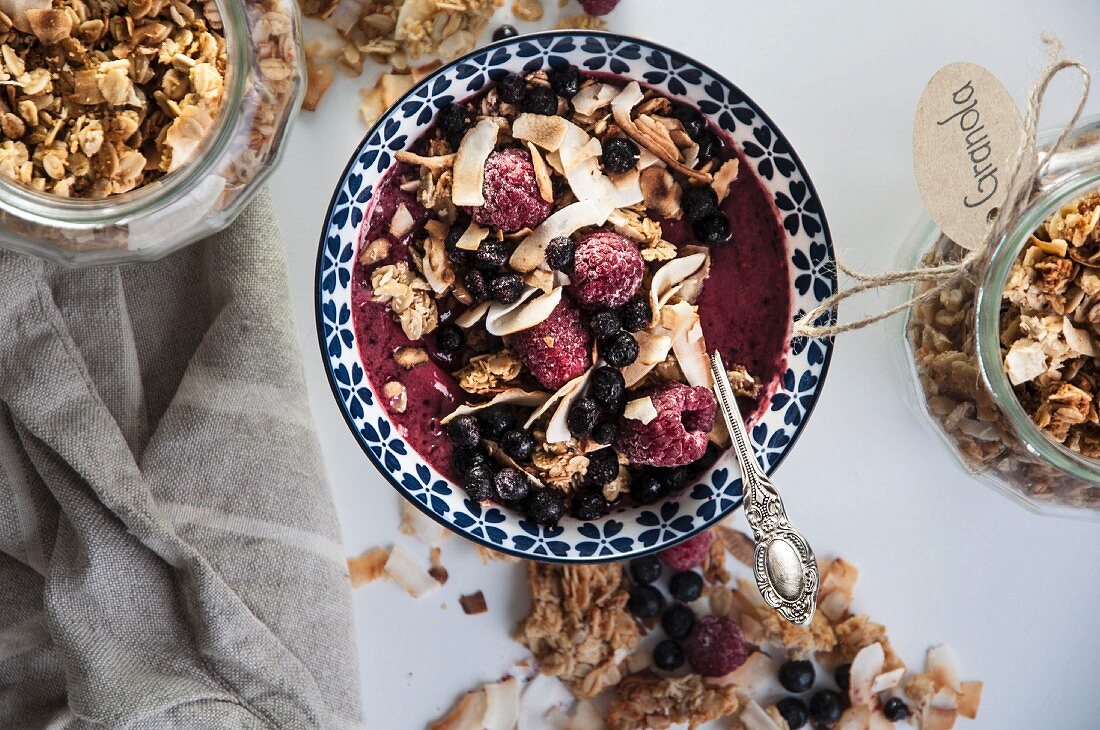 A smoothie bowl with granola, raspberries and blueberries