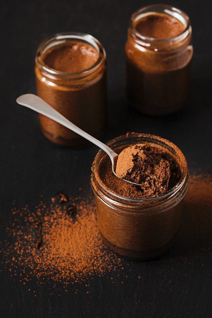 Chocolate mousse in small jars on a black slate