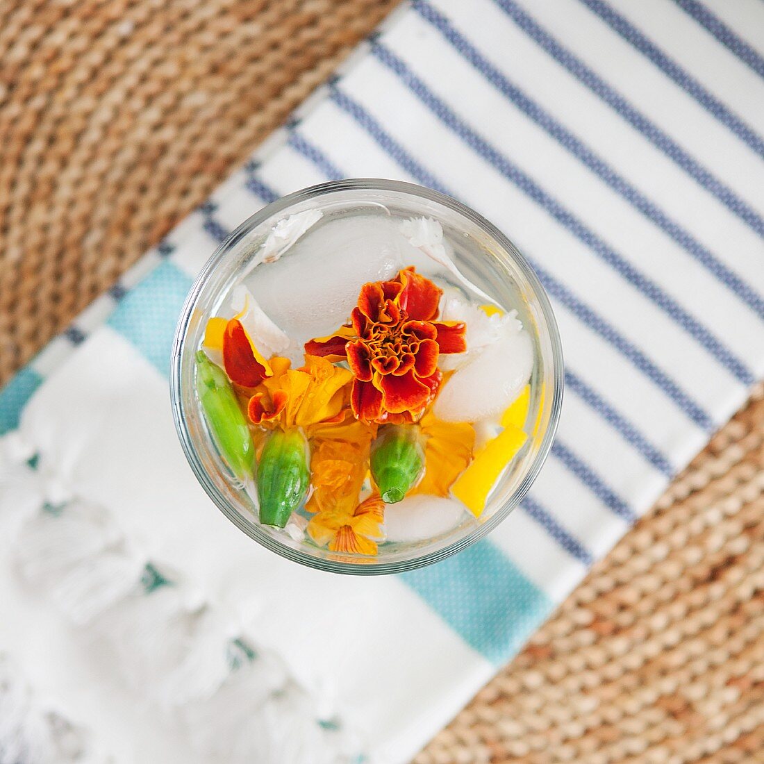 Mineral water in a glass infused with melon and edible flowers (top view)