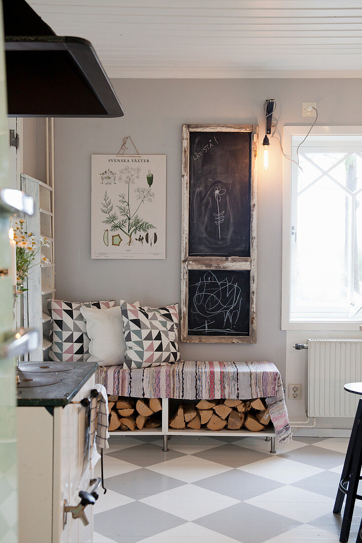 Chalkboards above bench with firewood below in country-house kitchen