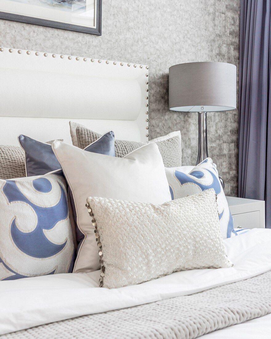 Pale grey, white and blue scatter cushions on double bed