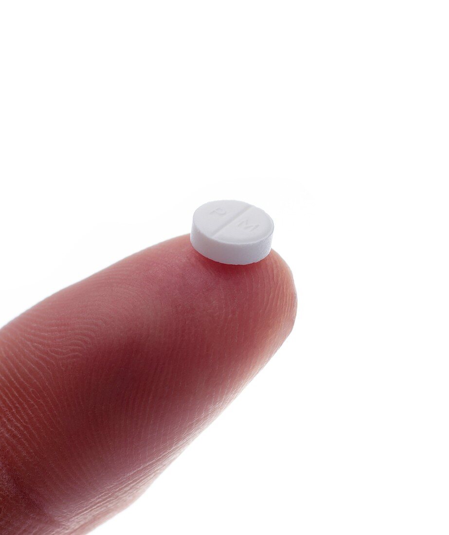 Single prednisolone tablet on a fingertip