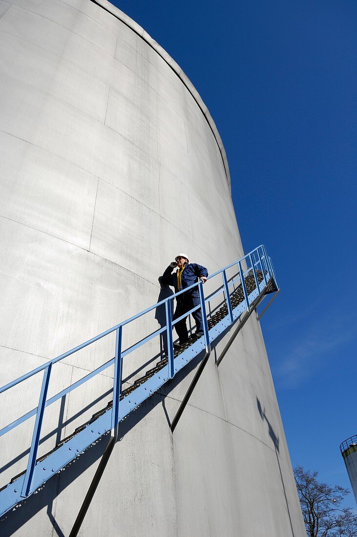 Man walking down steps on oil storage tower