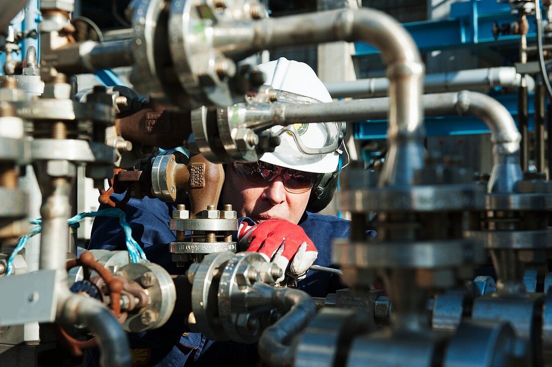Worker checking pump on an oil and gas refinery
