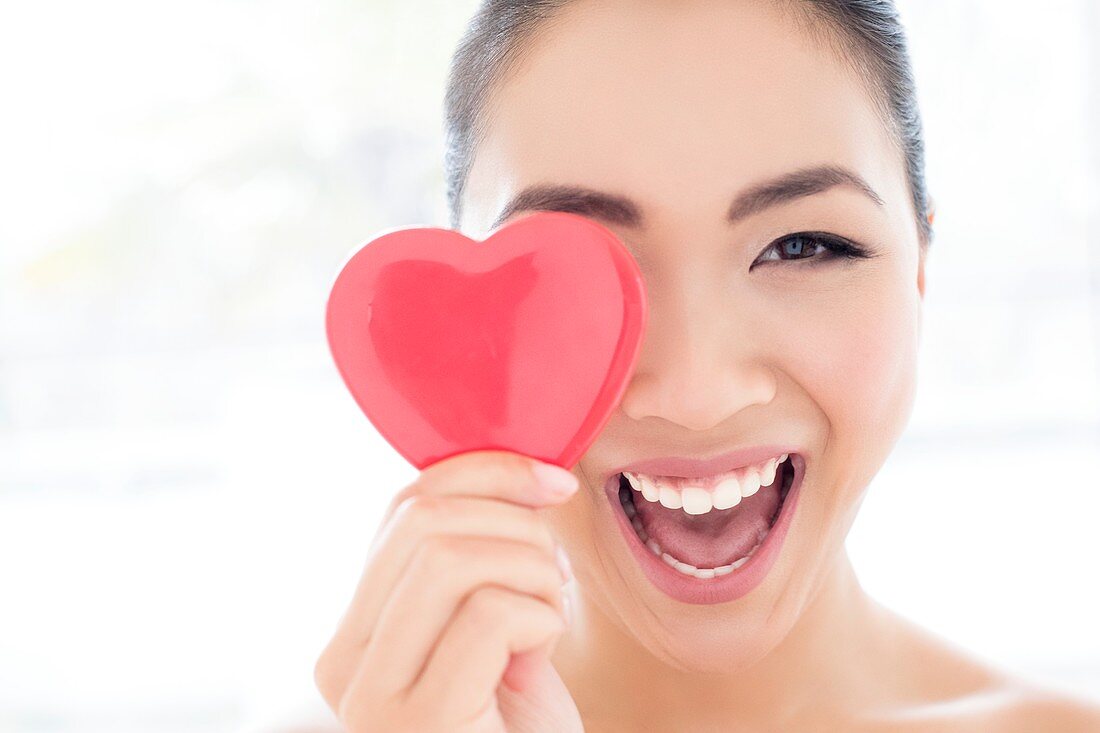 Woman covering eye with heart