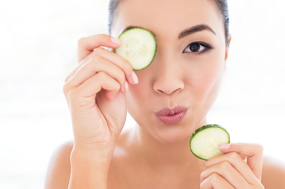 Woman holding cucumber in front of eye