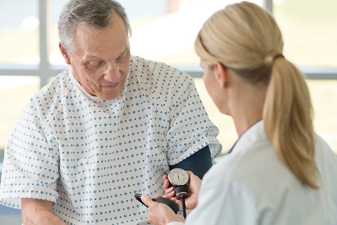 Female doctor taking senior man's blood pressure