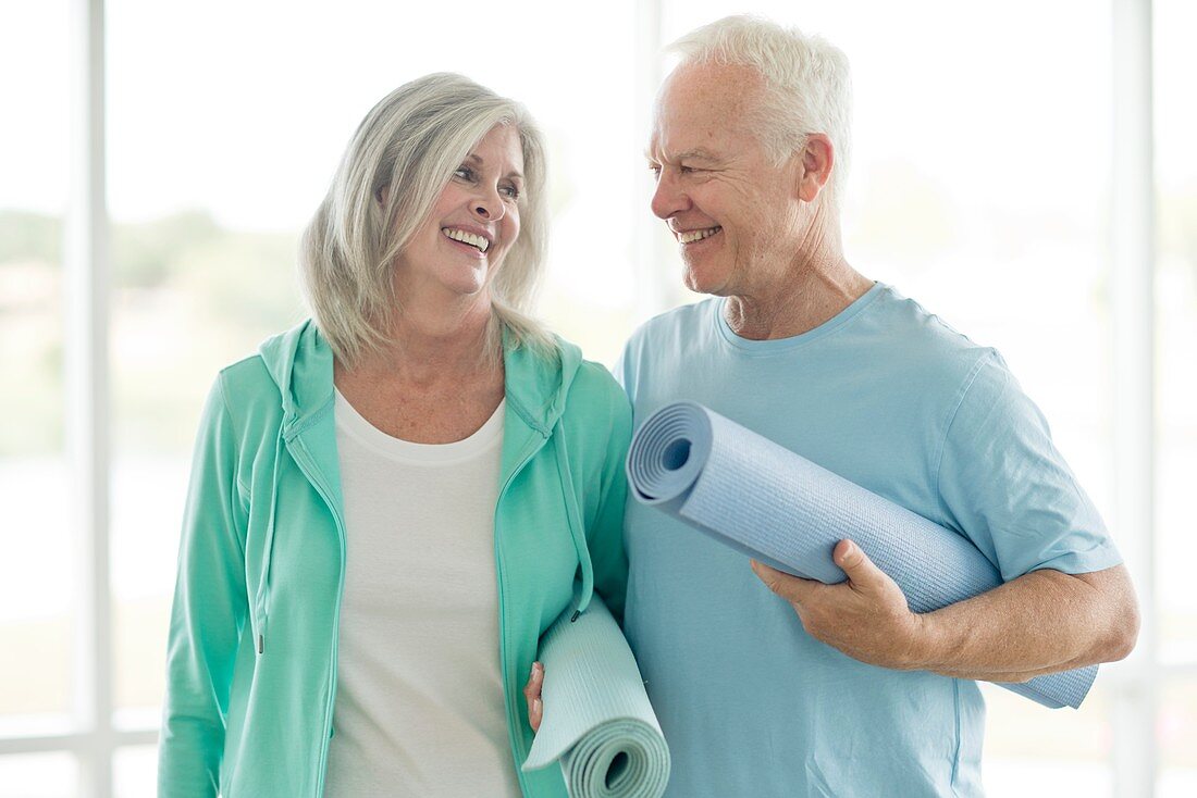 Senior couple holding yoga mats