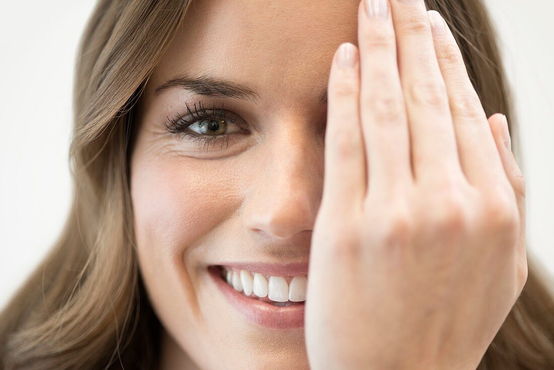 Mid adult woman covering eye with hand