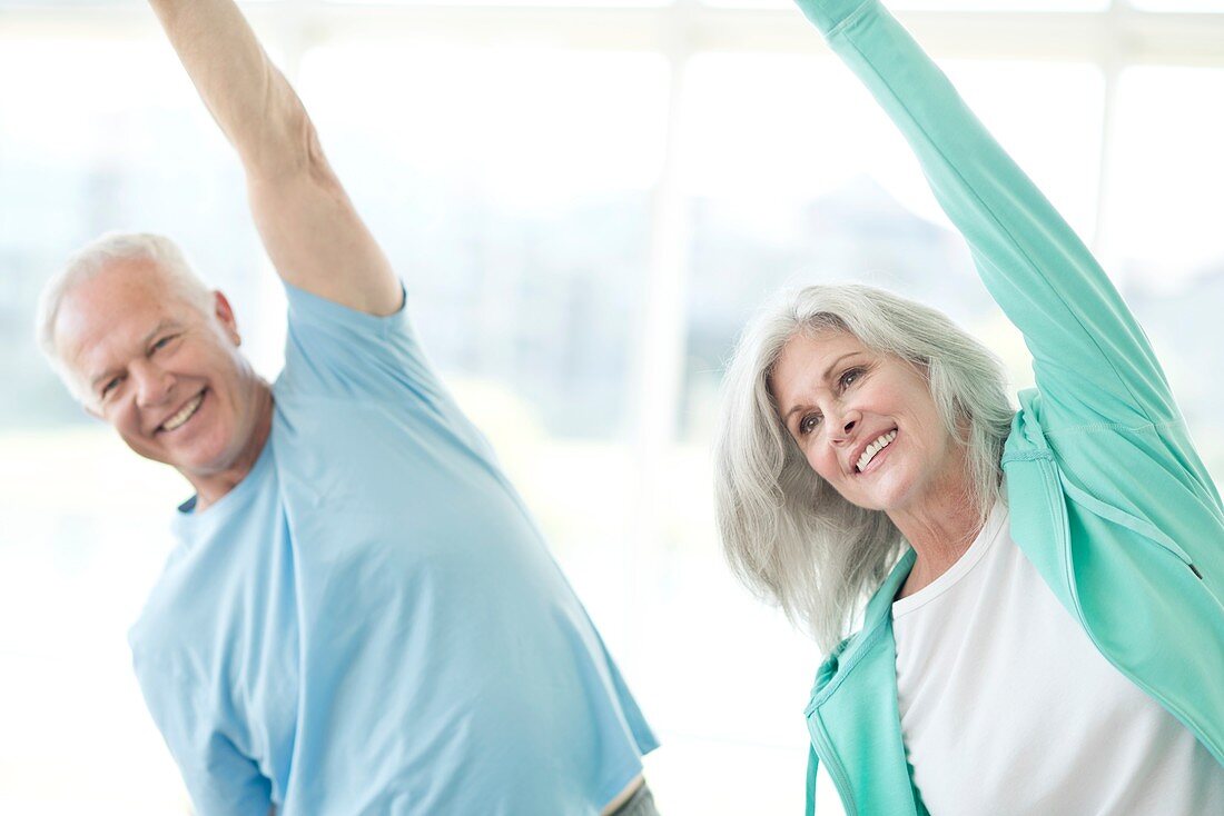 Senior couple stretching arms upwards