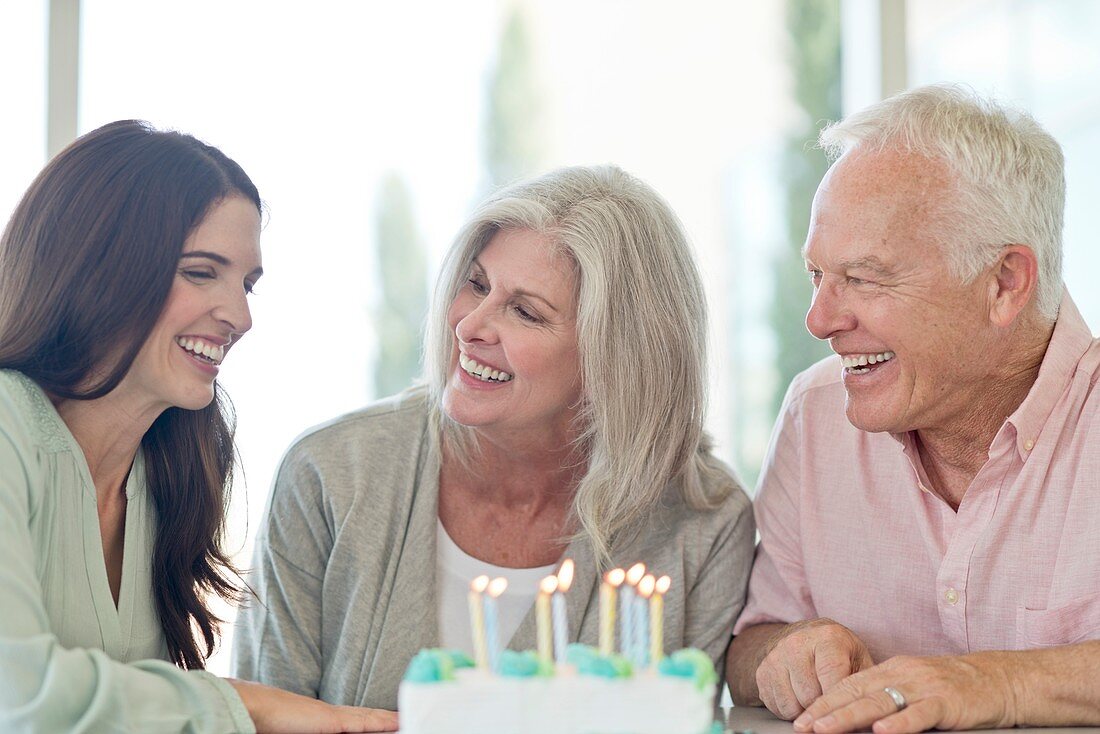 Senior couple and adult daughter with birthday cake