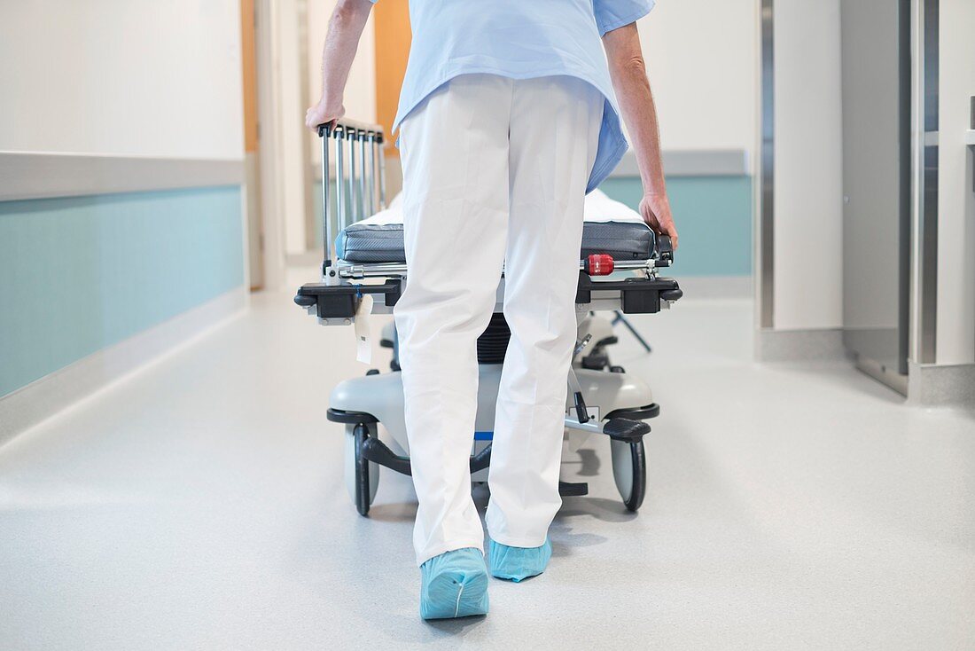 Nurse orderly pushing bed down corridor