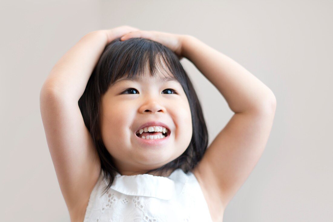 Young girl with hands on head smiling