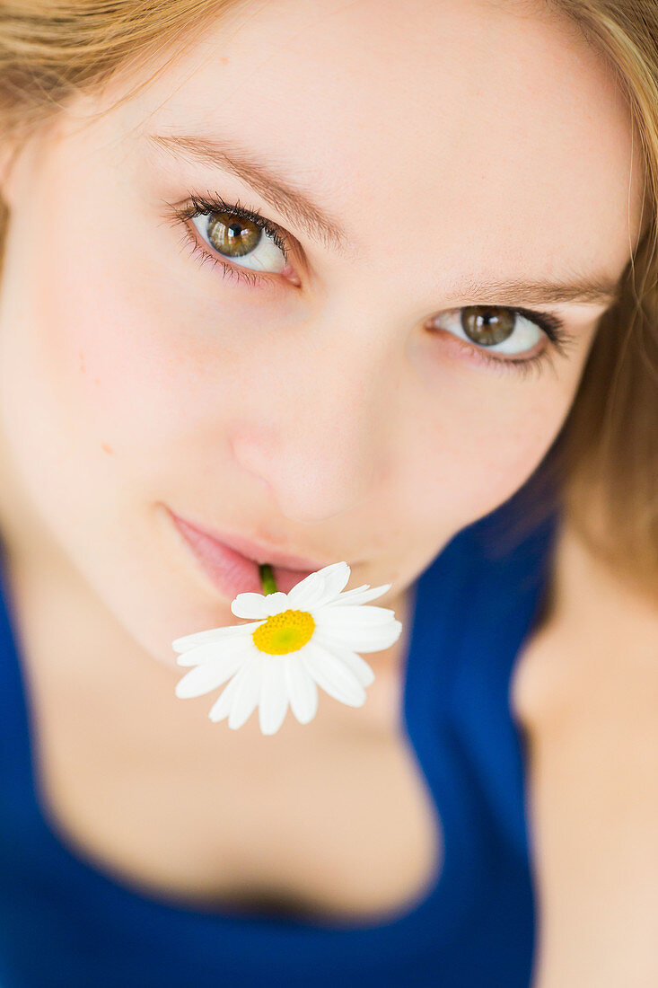 Woman holding a daisy in her mouth