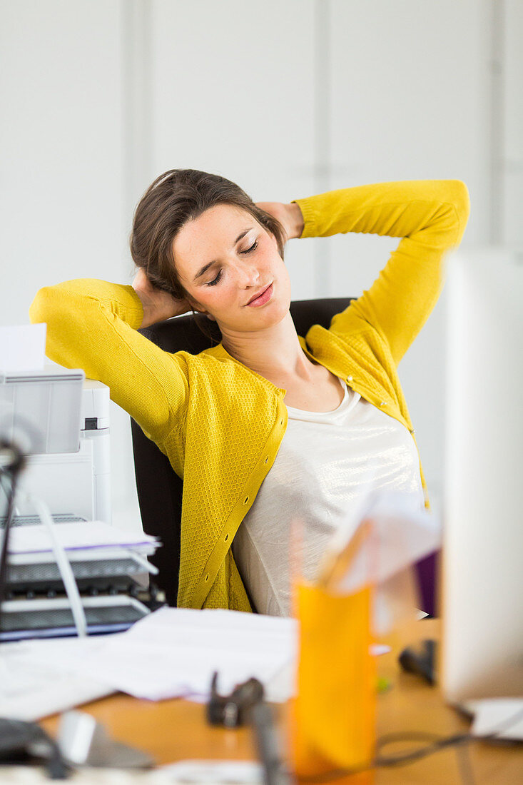 Woman relaxing and stretching arms at work