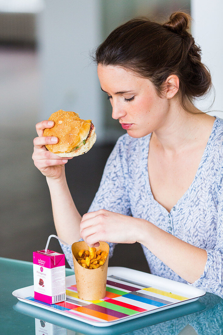 Woman eating hamburger and french fries