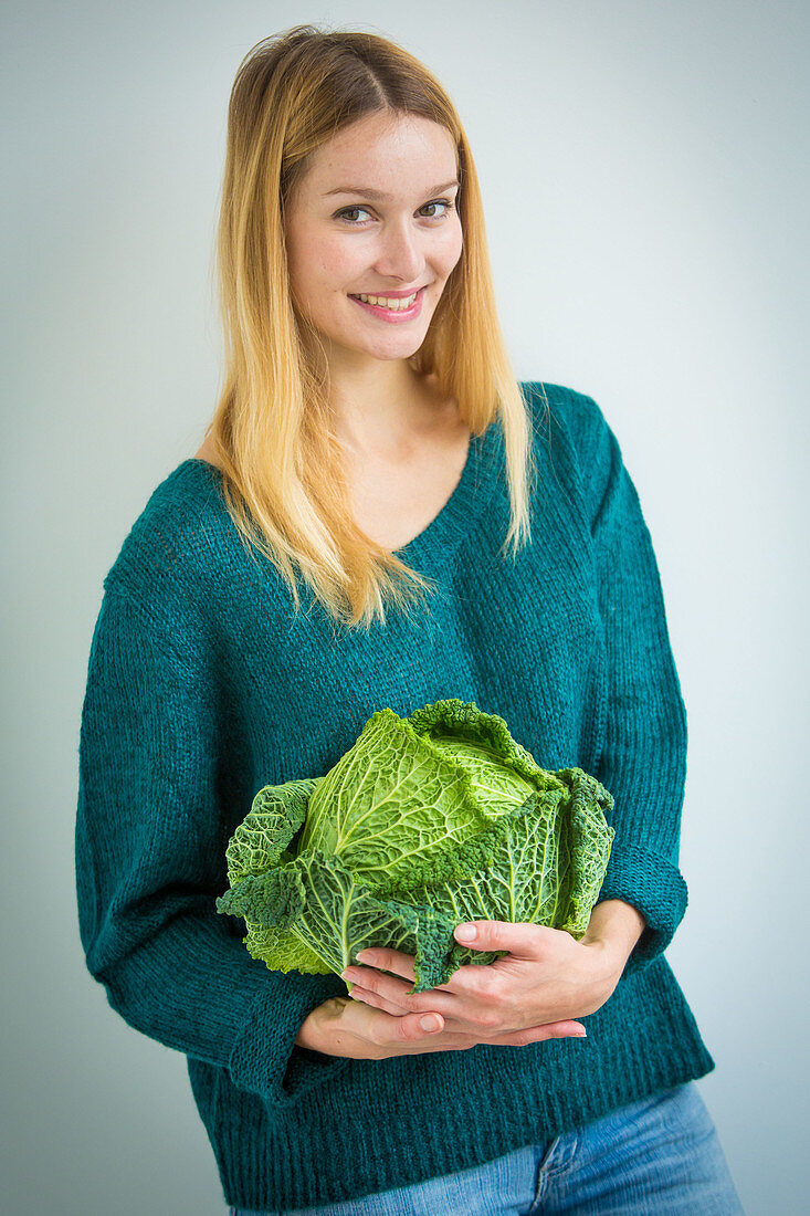 Woman holding green cabbage in her arms