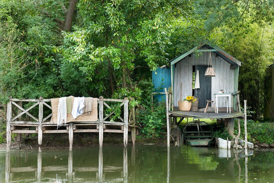 Rustic fisherman's hut and wooden jetty on shore of lake