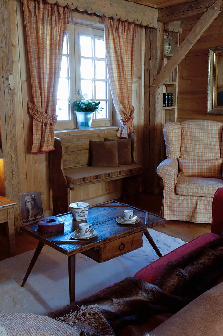 Alter Couchtisch mit Schublade und karierter Sessel im Chalet