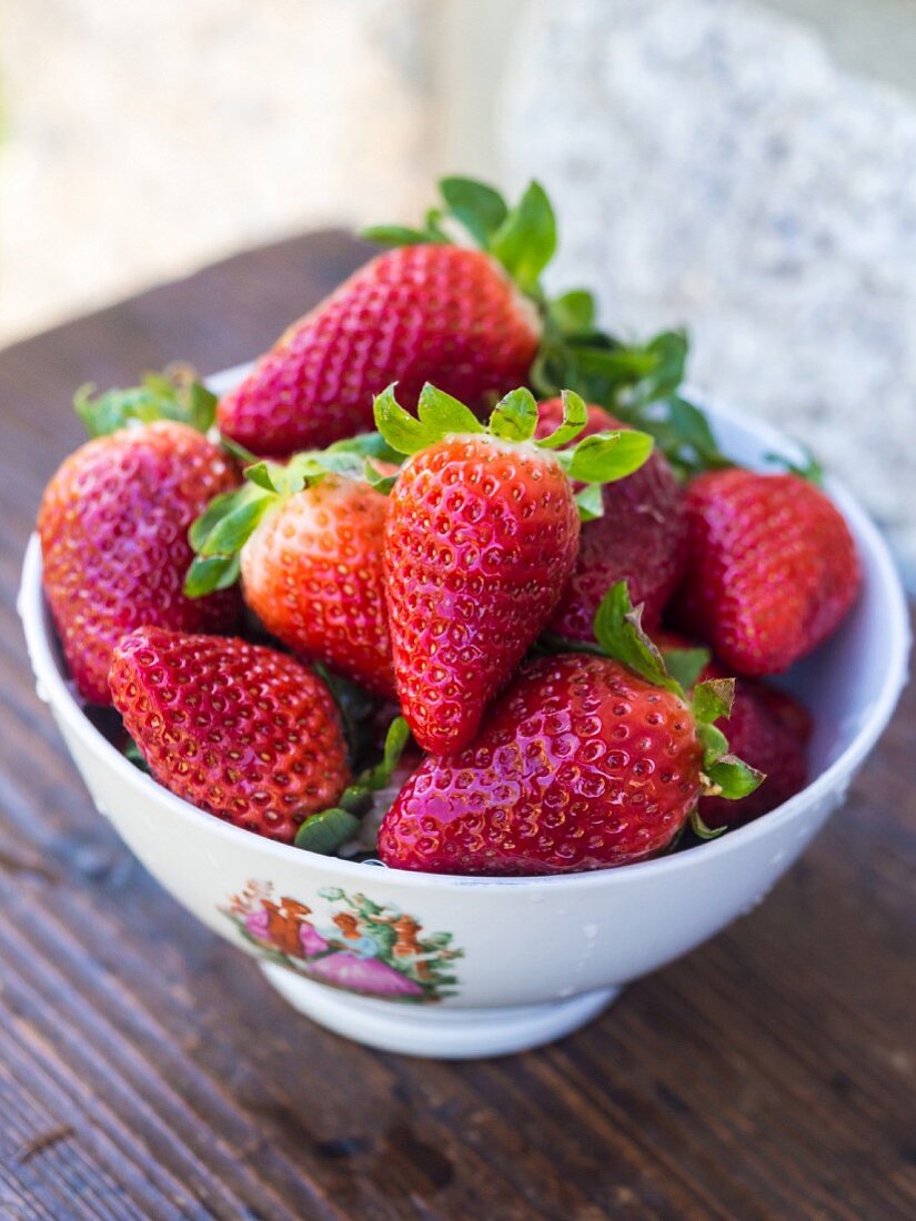 Fresh strawberries in a bowl on a table outdoors