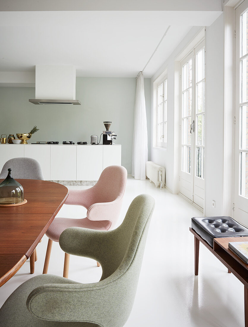 Chairs with pastel upholstery in front of modern open-plan kitchen