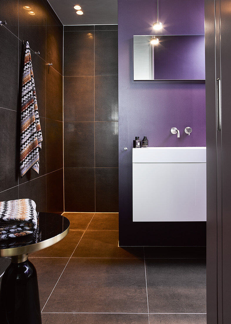 Modern bathroom with black tiled and purple wall