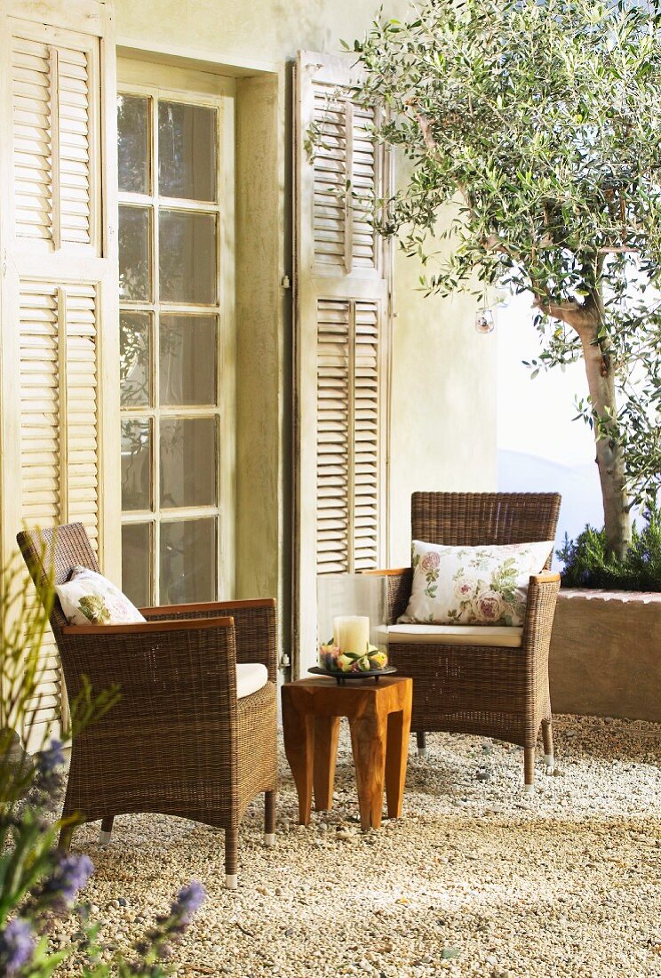 Zwei Korbstühle und ein Holztisch auf mediterraner Terrasse