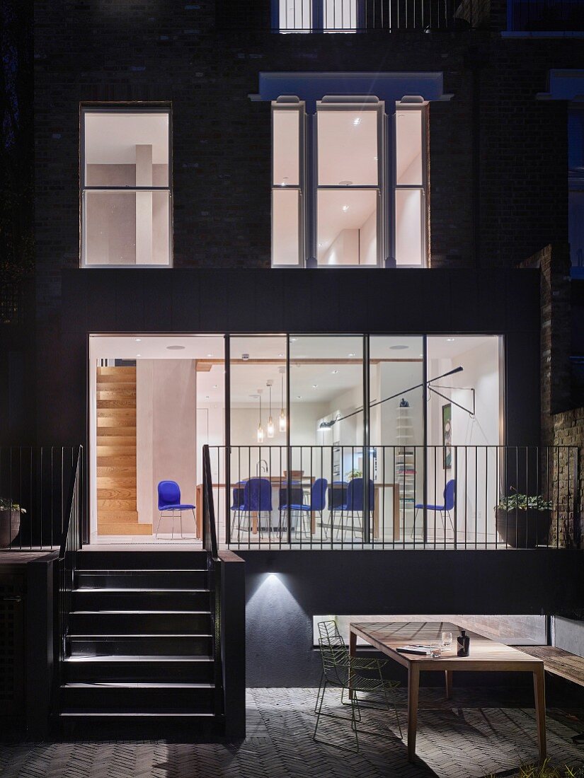 View from terrace into illuminated house with ground-floor dining area