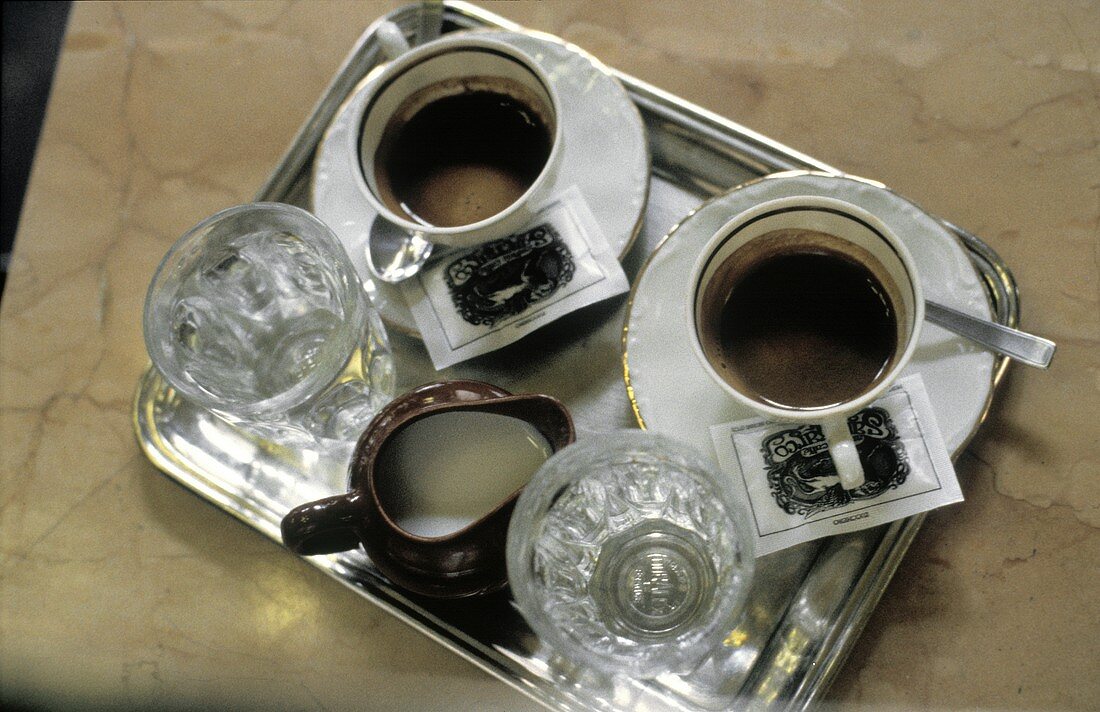 Zwei Tassen Espresso; Milchkännchen; Wassergläser auf Tablett