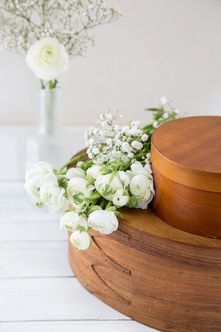 White ranunculus and gypsophila on brown chip-wood boxes