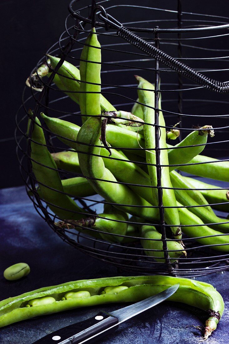 Green beans in an old wire basket against a black background