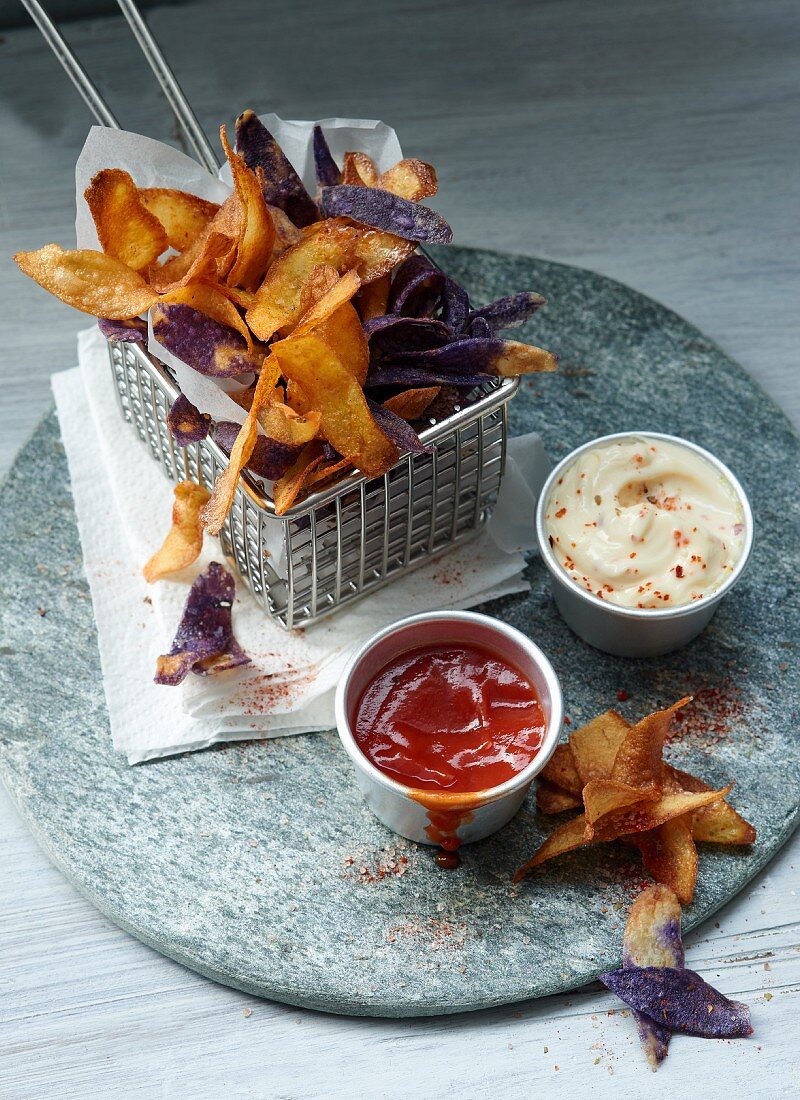 Colourful potato crisps with ketchup and chilli mayonnaise