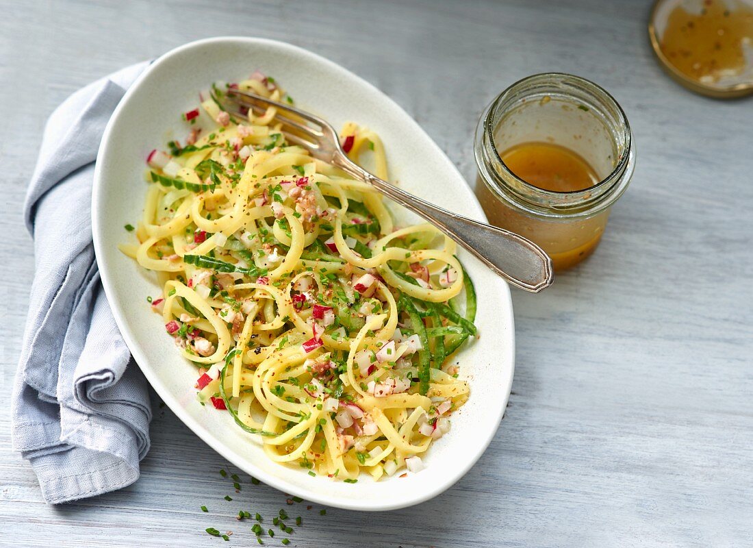 Gestreifter Kartoffelsalat mit einem Gläschen Dressing