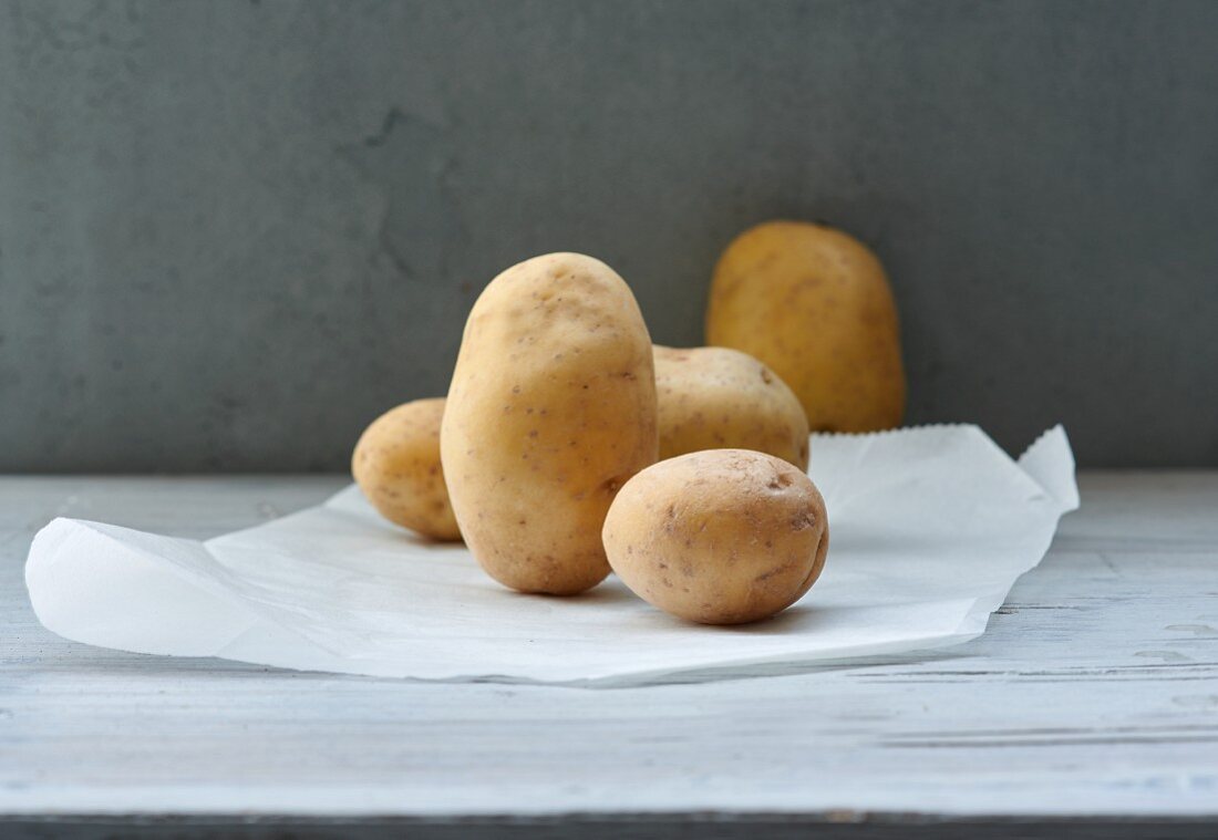 Several cooking potatoes on a piece of paper