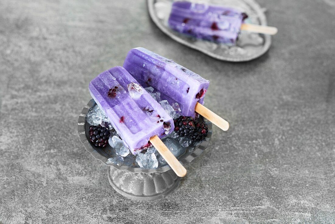 Blackberry ice lollies with fresh blackberries on crushed ice