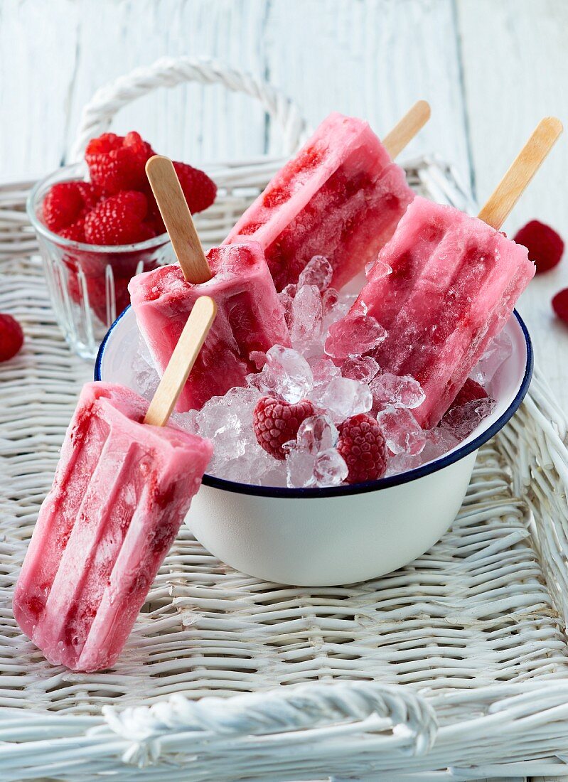 Summer raspberry ice lollies on sticks with fresh raspberries on crushed ice