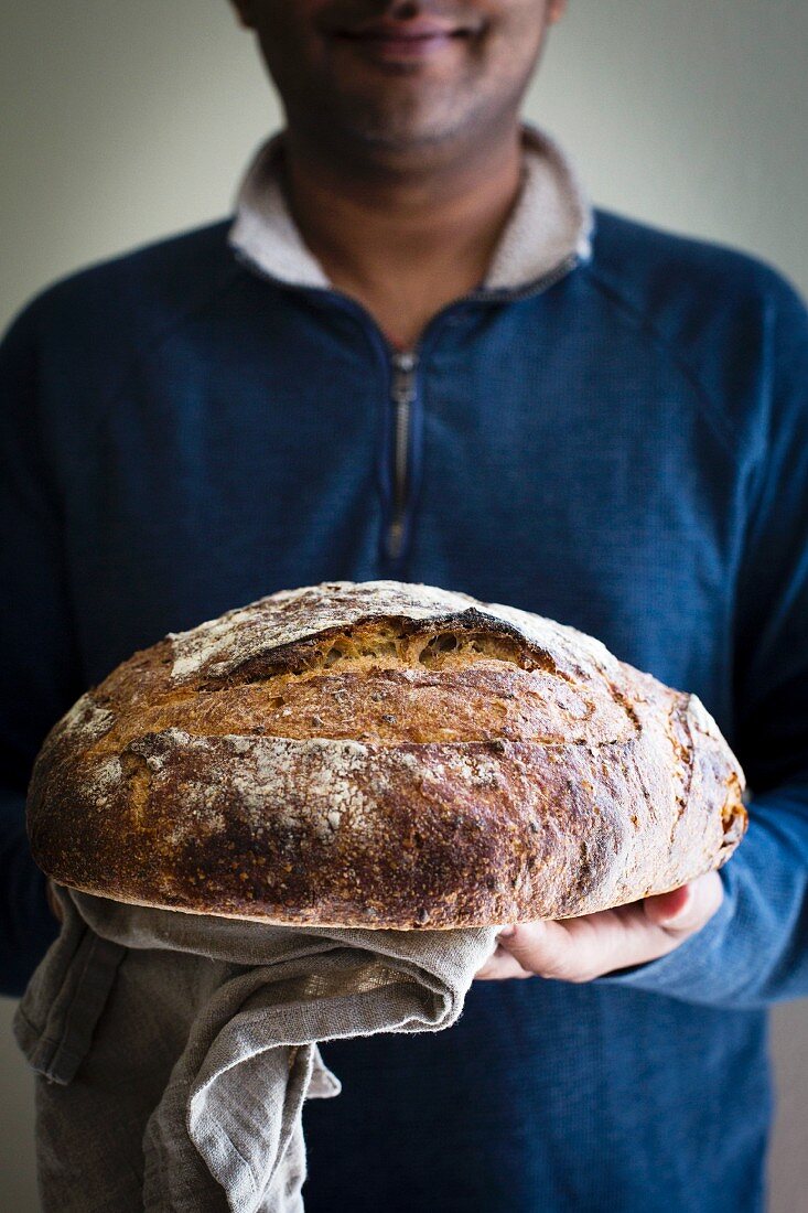 Man holding freshly baked sourdough bread front view