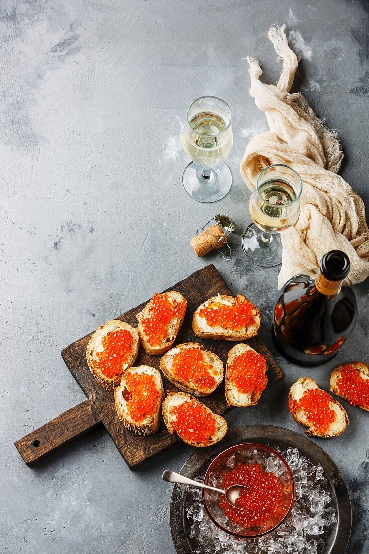 Sandwiches with salmon red caviar and champagne on concrete background