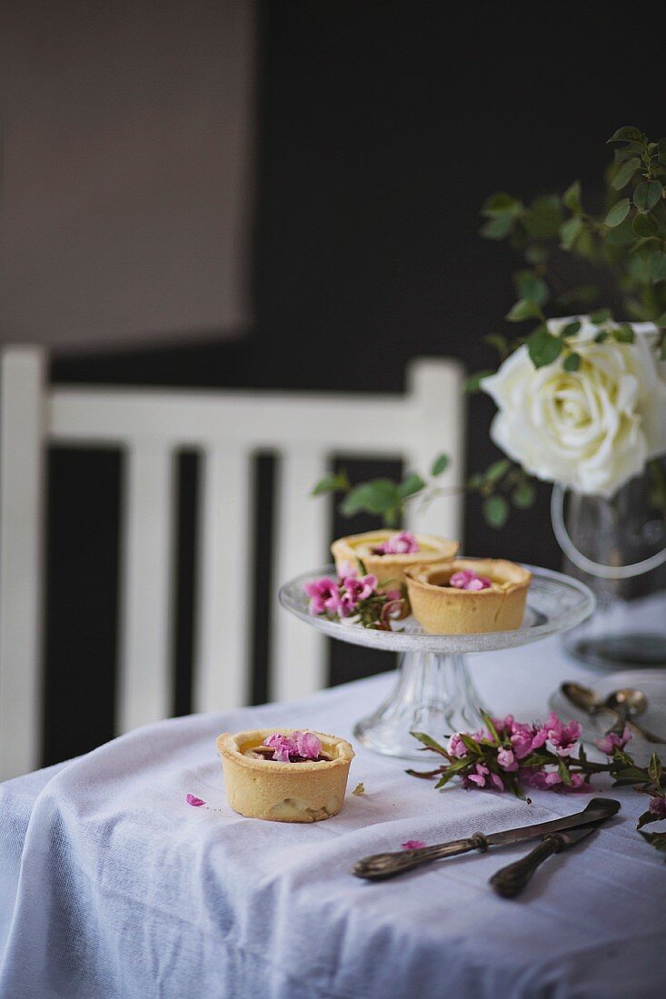 Torteletts mit Ricotta und Marmelade dekoriert mit Blüten auf Tisch