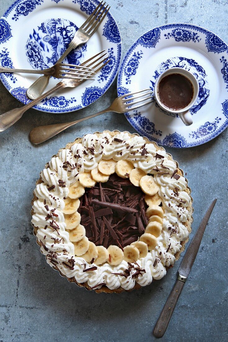 Chocolate banana cream pie on a pan with blue plates and cutlery