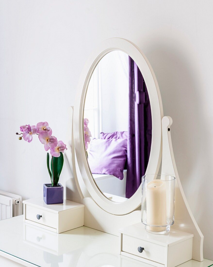 Oval mirror on dressing table in room with purple accents