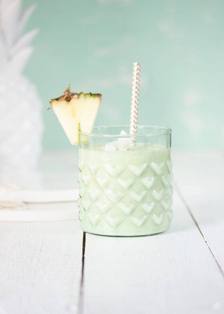 A pale green pineapple smoothie in a glass