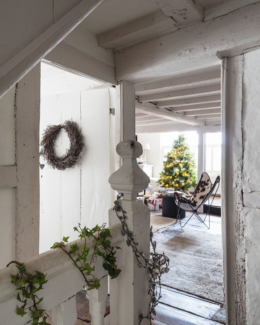 Vintage Treppenhaus mit Efeu und Türkranz dekoriert, Blick in Wohnbereich mit Weihnachtsbaum