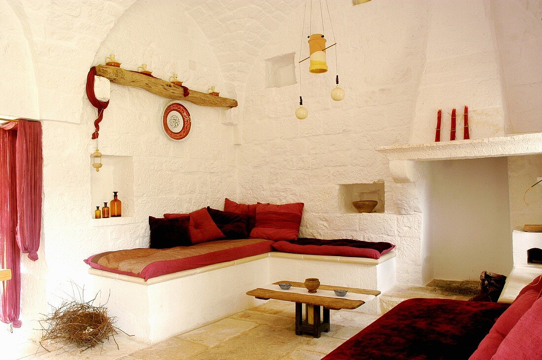 Whitewashed lounge with red accents in renovated trullo