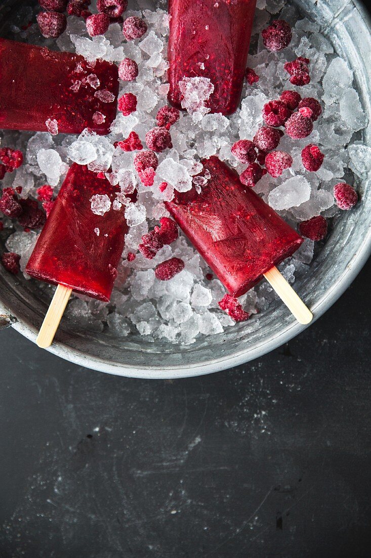 Raspberry ice lollies on sticks in an ice bucket