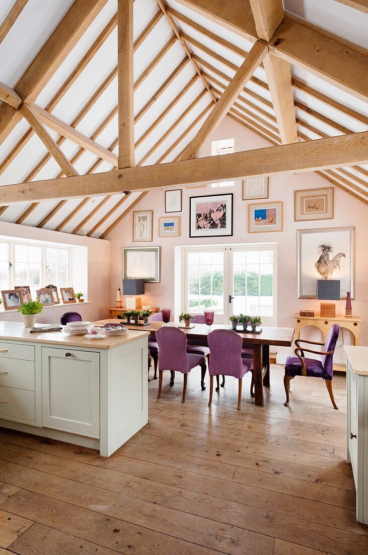 Large dining table below open roof structure in kitchen-dining room