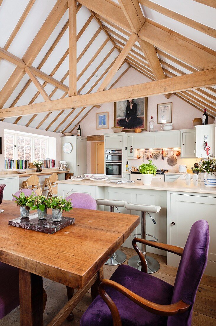 Dining table in country-house kitchen-dining room below open roof structure